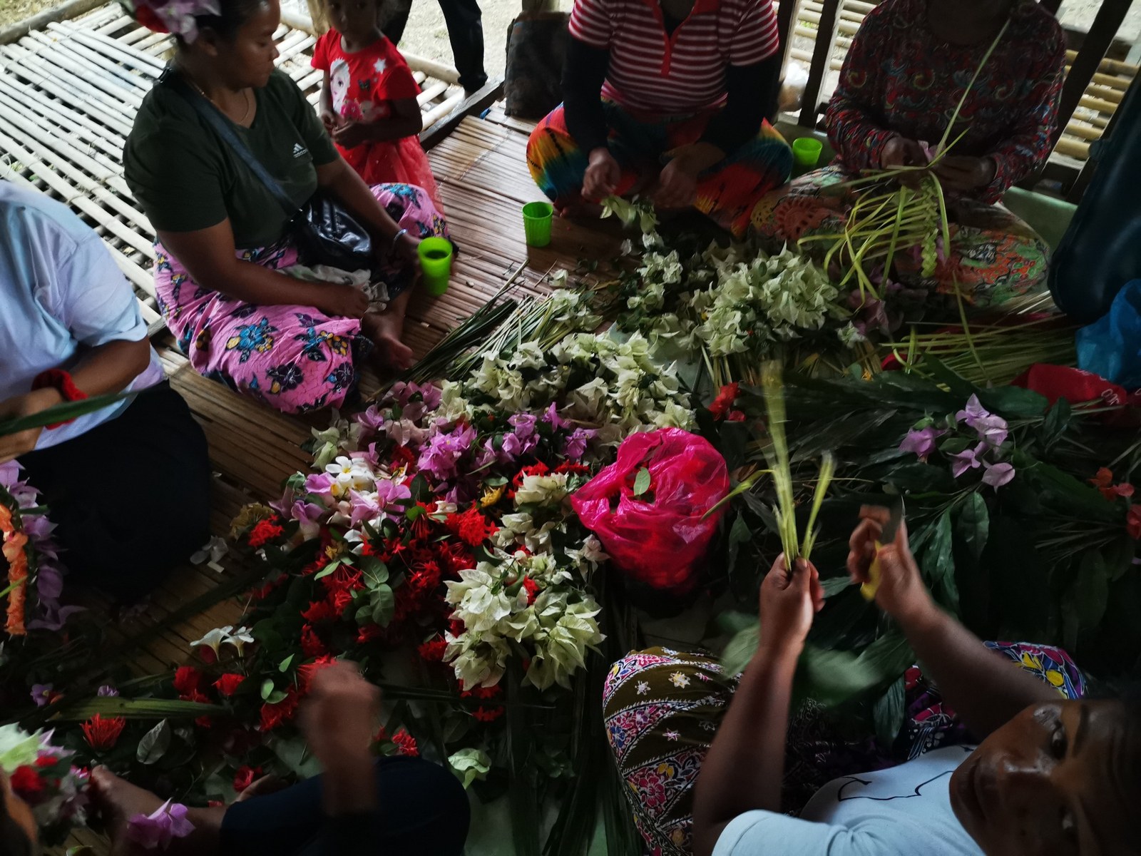 People sitting together preparing flowers and leaves for gabag