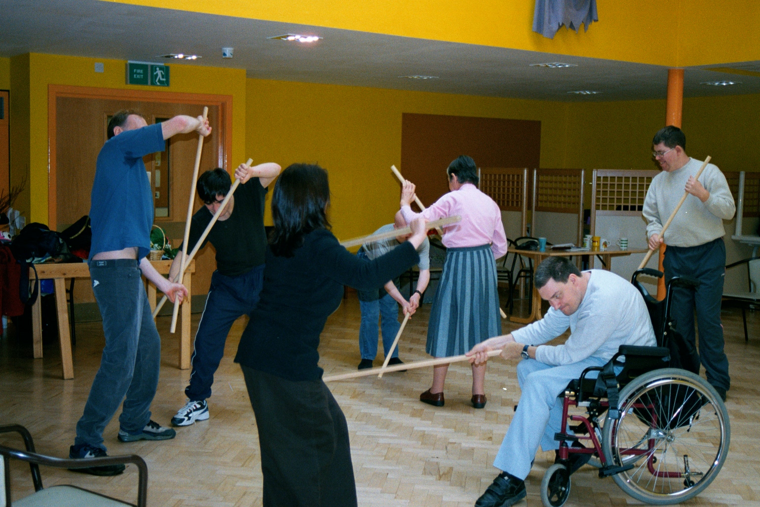 Participants engaged in an energetic group drama activity involving long wooden sticks.
